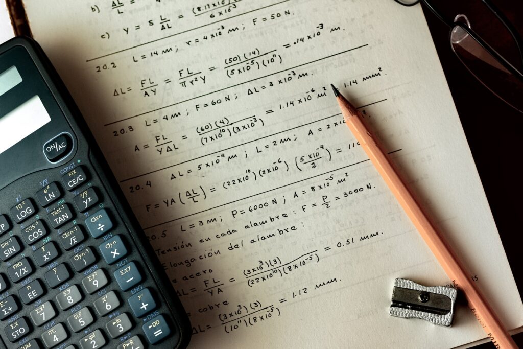 A page of equations surrounded by a pencil and calculator